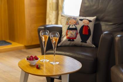 Chambre avec lit queen size, mur en pierre apparente, coussins décoratifs, lampes murales et fenêtre apportant lumière naturelle